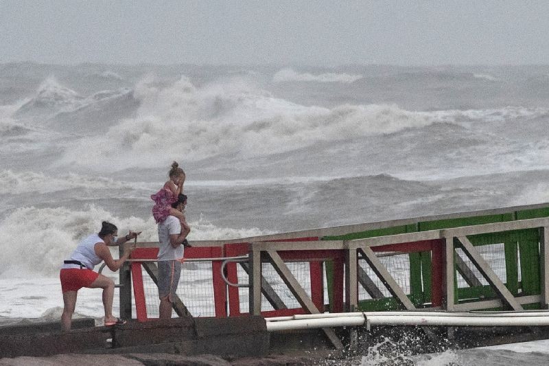A girl covers her face from strong winds as her family members watch high swells from Hurricane Hanna from a jetty in Galveston, Texas, U.S., July 25, 2020. REUTERS/Adrees Latif